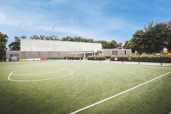 De kunstgrasvelden van Spirit met sporthal De Voorde erachter